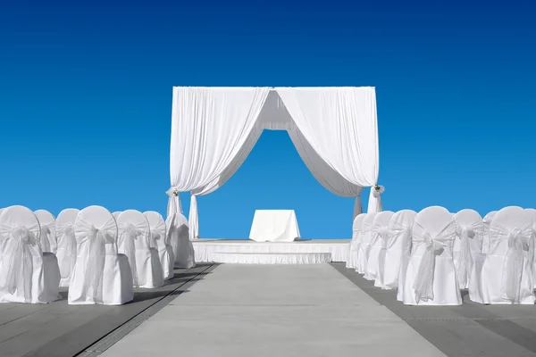 Canopy de boda con sillas, todo en blanco sobre cielo azul Imagen de archivo