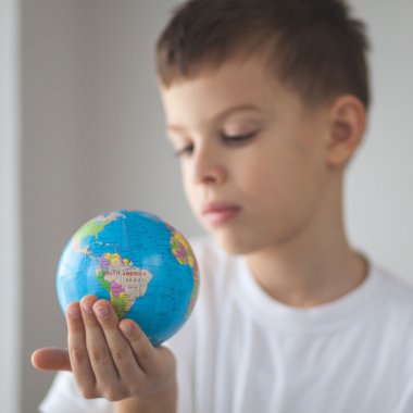 Çocuk oyuncak globus elinde tutan. Gün doğal pencere ışık