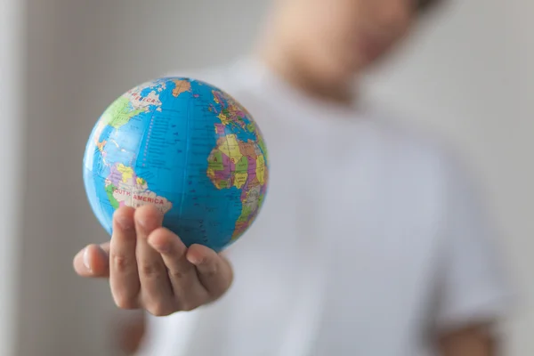 Çocuk oyuncak globus elinde tutan. Gün doğal pencere ışık