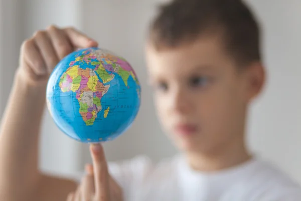 Ragazzo che tiene in mano un globus giocattolo. Giorno luce naturale della finestra Foto Stock