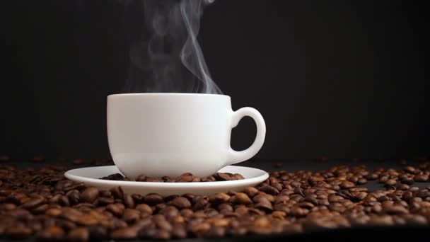 Tasse mit Heißgetränk auf gerösteten Kaffeebohnen. Kugelstoßer — Stockvideo