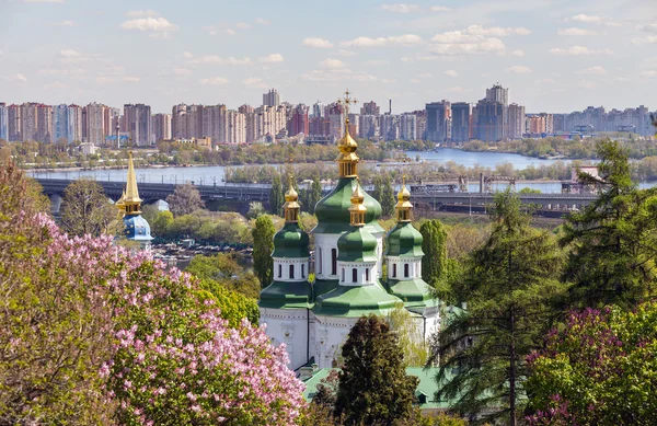 Catedral de São Jorge do Mosteiro de Vydubychi entre as árvores do parque contra um moderno edifício de apartamentos primavera. Kiev, Ucrânia . — Fotografia de Stock