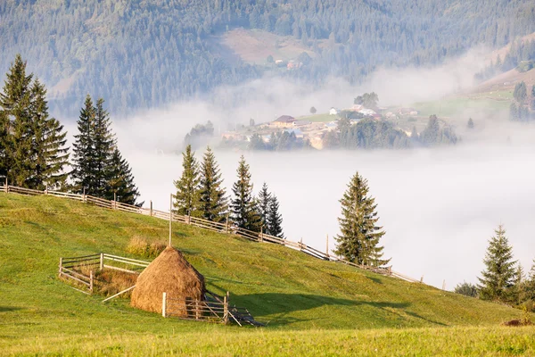 Amazing scenery of idyllic countryside with rolling hills veiled in morning fog. Aerial view of a hilltop farmhouse on a foggy spring morning — Stock Photo, Image