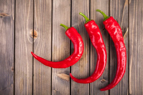 Pimientos rojos picantes sobre fondo de madera — Foto de Stock