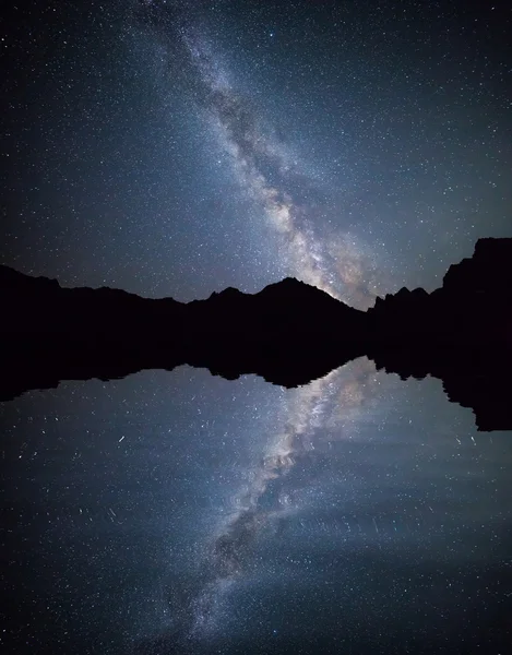 Night sky full of stars reflecting on the water surface.