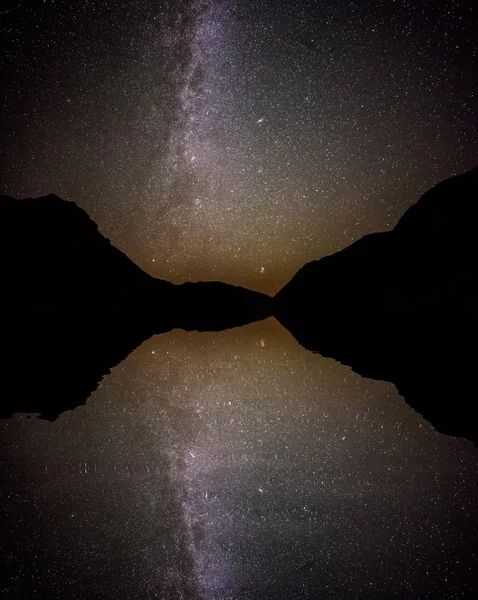 Céu noturno cheio de estrelas refletindo sobre a superfície da água . — Fotografia de Stock