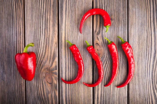 Chiles rojos picantes y pimientos sobre fondo de madera — Foto de Stock