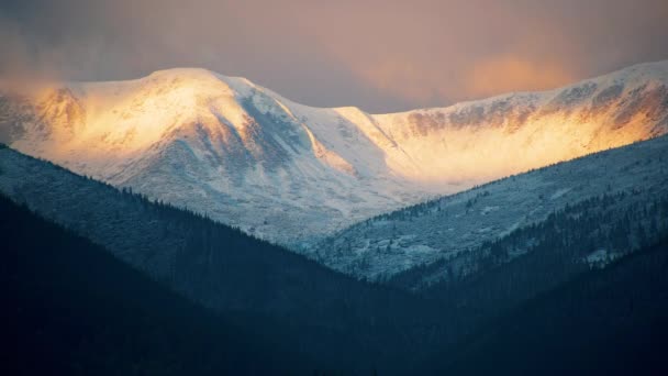 Blick auf einen Winterbergrücken nach Sonnenaufgang. Schneebedeckte Bergspitze bei Sonnenuntergang. Makelloser farbiger Schnee. — Stockvideo