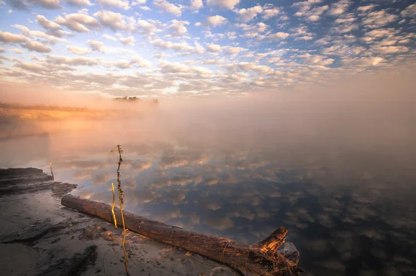 Mistige ochtend op de rivier en de wolken weerspiegeld in water — Stockfoto