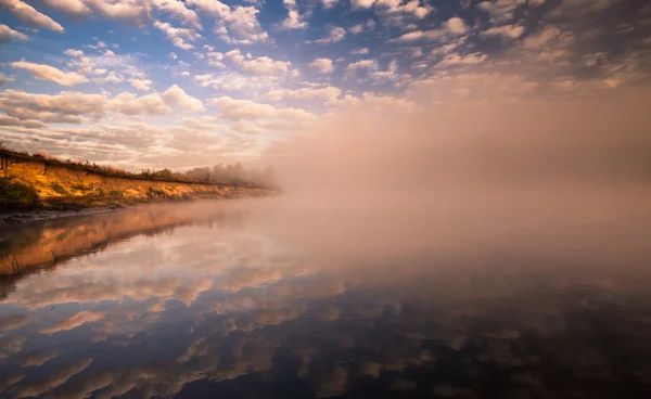 Manhã enevoada no rio e nuvens refletidas na água — Fotografia de Stock