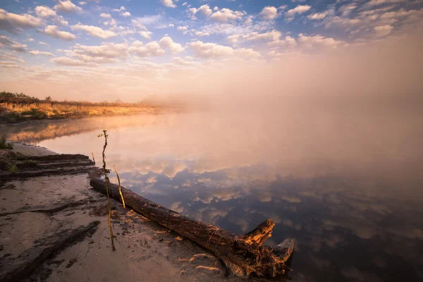 Mistige ochtend op de rivier en de wolken weerspiegeld in water — Stockfoto