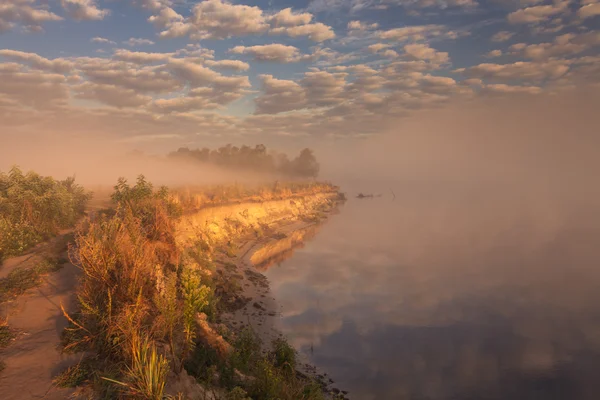 Mistige ochtend op de rivier en de wolken weerspiegeld in water — Stockfoto