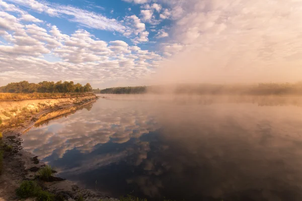 Nebliger Morgen auf dem Fluss und Wolken, die sich im Wasser spiegeln — Stockfoto