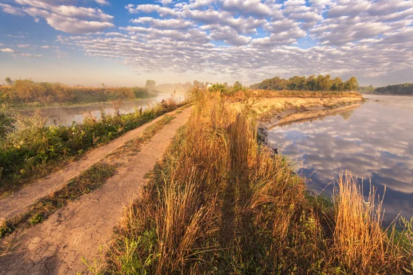 Dimmig morgon vid floden och moln återspeglas i vatten — Stockfoto