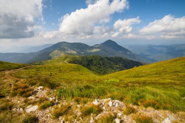 Dağlardaki yaz manzarası ve bulutlu koyu mavi gökyüzü.