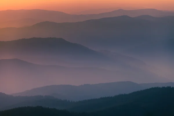 Distant mountain range and thin layer of clouds on the valleys — Stock Photo, Image