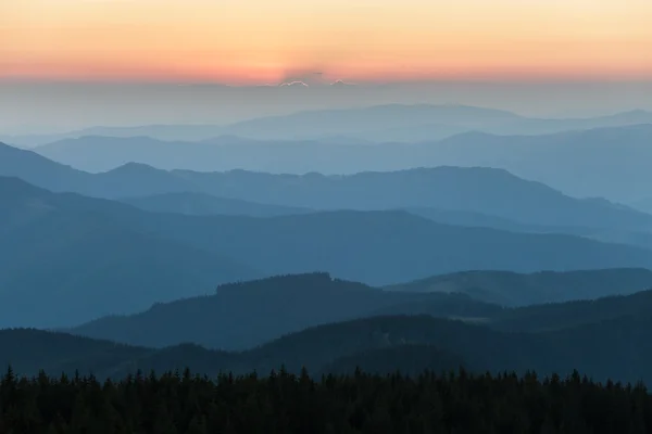 Distant mountain range and thin layer of clouds on the valleys — Stock Photo, Image