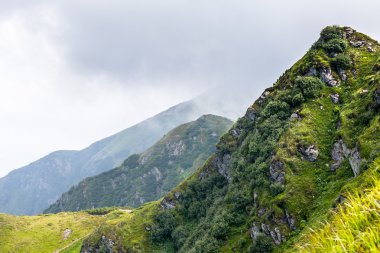 Dağlardaki yaz manzarası ve bulutlu koyu mavi gökyüzü.