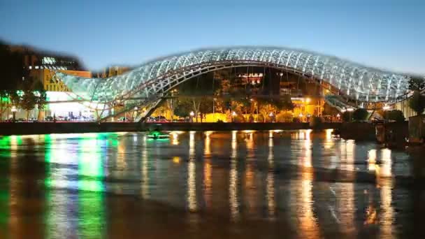 TBILISI, GEORGIA - JULY 29, 2015: Night view of the brightly lit bridges of Peace. The bridge stretches over the Mtkvari river and connects the areas of old Tbilisi — Stock Video