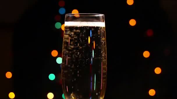 Bubblor inuti ett glas champagne mot bakgrund av semester lampor — Stockvideo