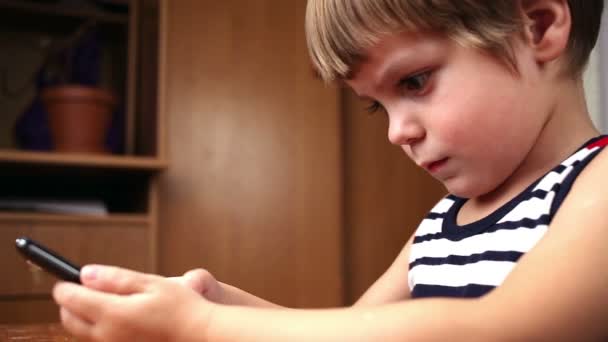 Liten pojke spelar och vidrör en mobiltelefon — Stockvideo