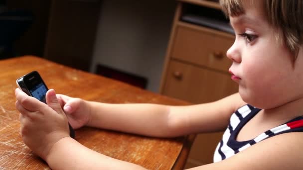 Маленький хлопчик грає і торкається мобільного телефону — стокове відео