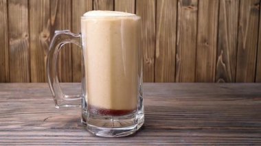 Ahşap arka plan üzerinde bir bardak içine bira dökmek