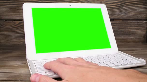 Een man typt op een laptop op zijn bureau. groen scherm voor uw aangepaste scherminhoud — Stockvideo