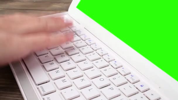 Een man typt op een laptop op zijn bureau. groen scherm voor uw aangepaste scherminhoud — Stockvideo