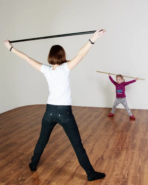 Lille pige laver træning med en pind med en træner på - Stock-foto