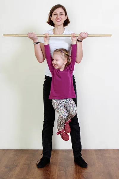 Entrenador está sosteniendo un palo, niña está colgando de ella, stretc — Foto de Stock