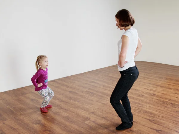 Trainer and a little girl are dancing at the gym