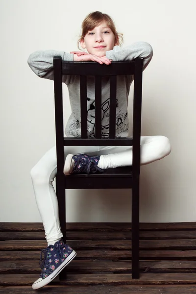 La niña está sentada en la silla, sonriendo — Foto de Stock