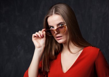 Kadın güneş gözlüğü, gri arka plan üzerinde arıyor