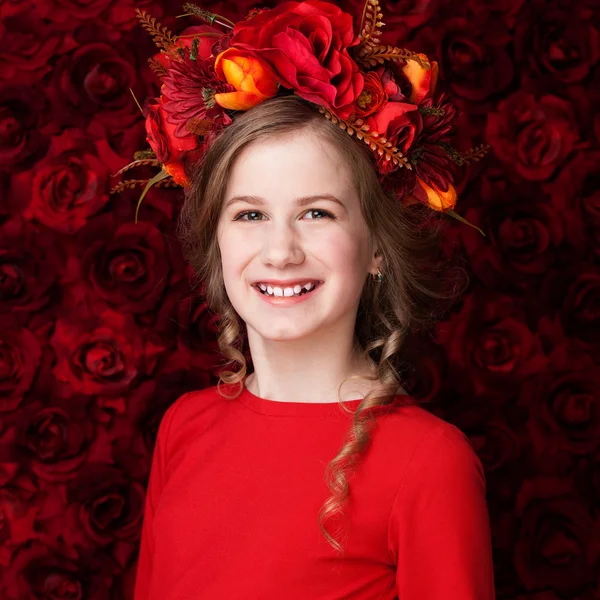 Porträtt av en liten söt flicka i en blomsterkrans, leende — Stockfoto