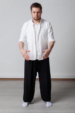 Genç adam beyaz gömlek ve siyah pantolon tai chi egzersiz gerçekleştirme