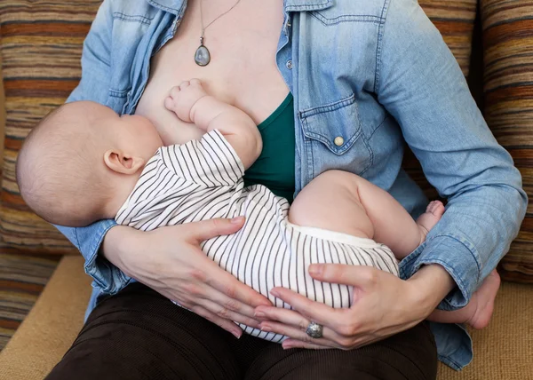 Femme tenant et nourrissant un bébé — Photo
