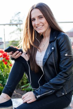  kadın siyah ceket ve kot taş parapetin üzerinde oturuyor