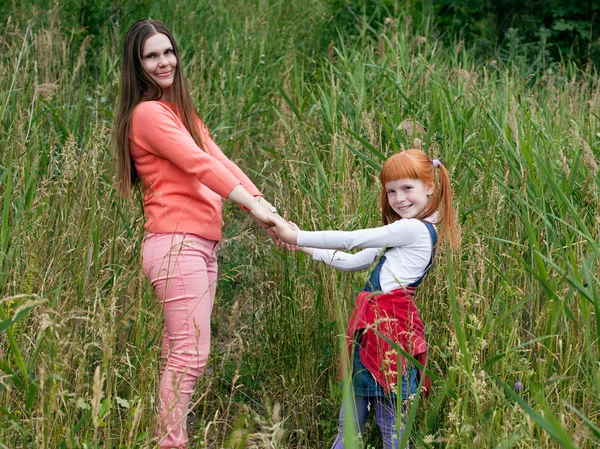 Feliz madre e hija tomados de la mano y mirando en el marco — Foto de Stock