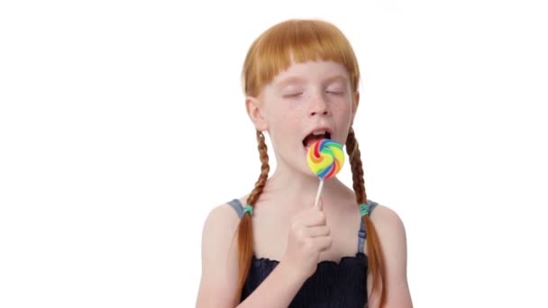 Little ginger girl is licking a lollypop — Stock Video