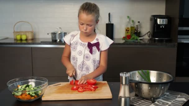 Маленькая девочка готовит салат на кухне — стоковое видео