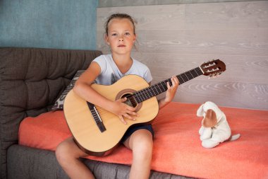 Küçük kız dizlerinin üzerinde bir gitar ile