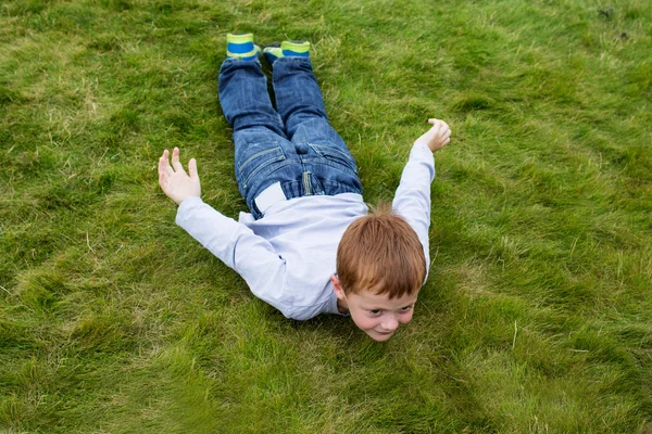 少年スライディング ポーズで草の上に敷設 — ストック写真