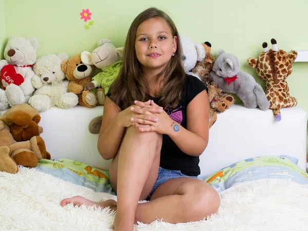 Симпатична дівчинка сидить на ліжку — стокове фото