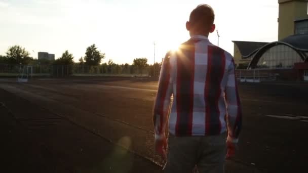 Guy is het oversteken van het stadion bij de zonsondergang — Stockvideo