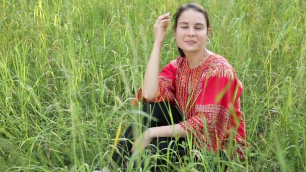 Mujer está sentado en la hierba alta — Vídeos de Stock