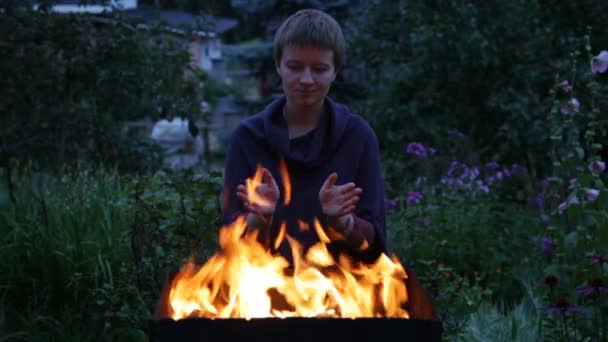 Жінка зігріває руки біля вогню — стокове відео