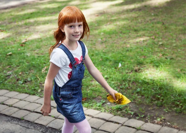 Pequeña chica pelirroja caminando en el camino — Foto de Stock