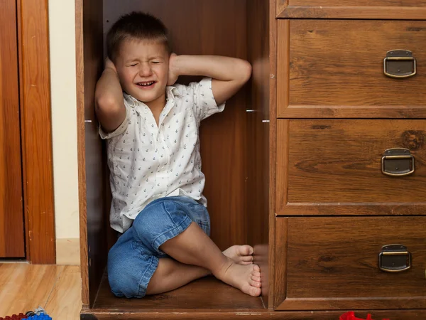 Little boy hiding in a cupboard and crying — Stock Photo, Image