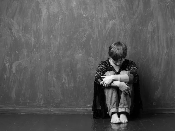 Inhemska våld - hopplös kvinna sitter mot väggen — Stockfoto
